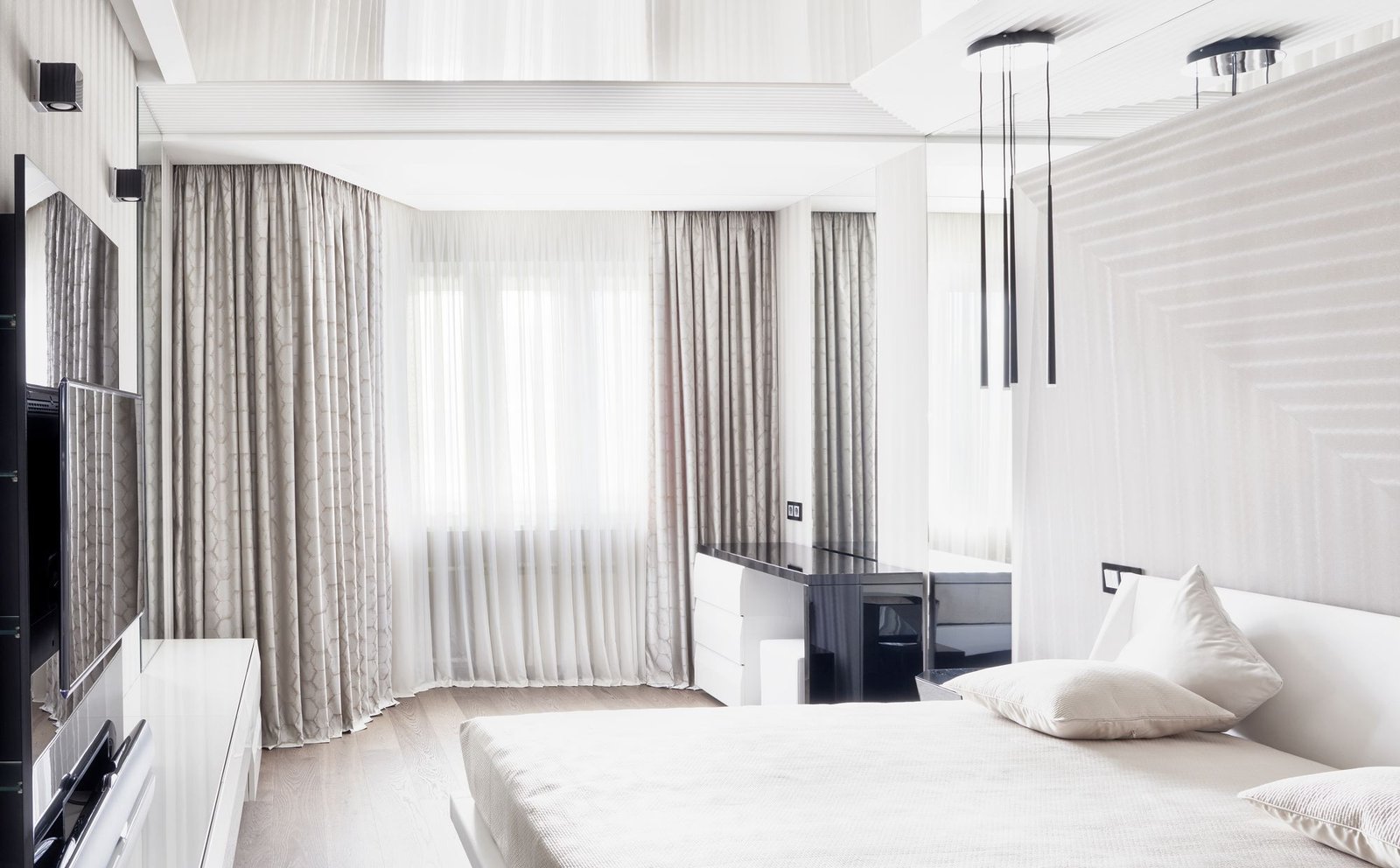 Floor-length white sheer curtains drawn across a minimal bedroom