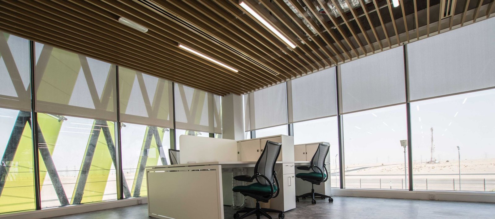 Infinity roller blinds lowered across the glazing of an open-plan office