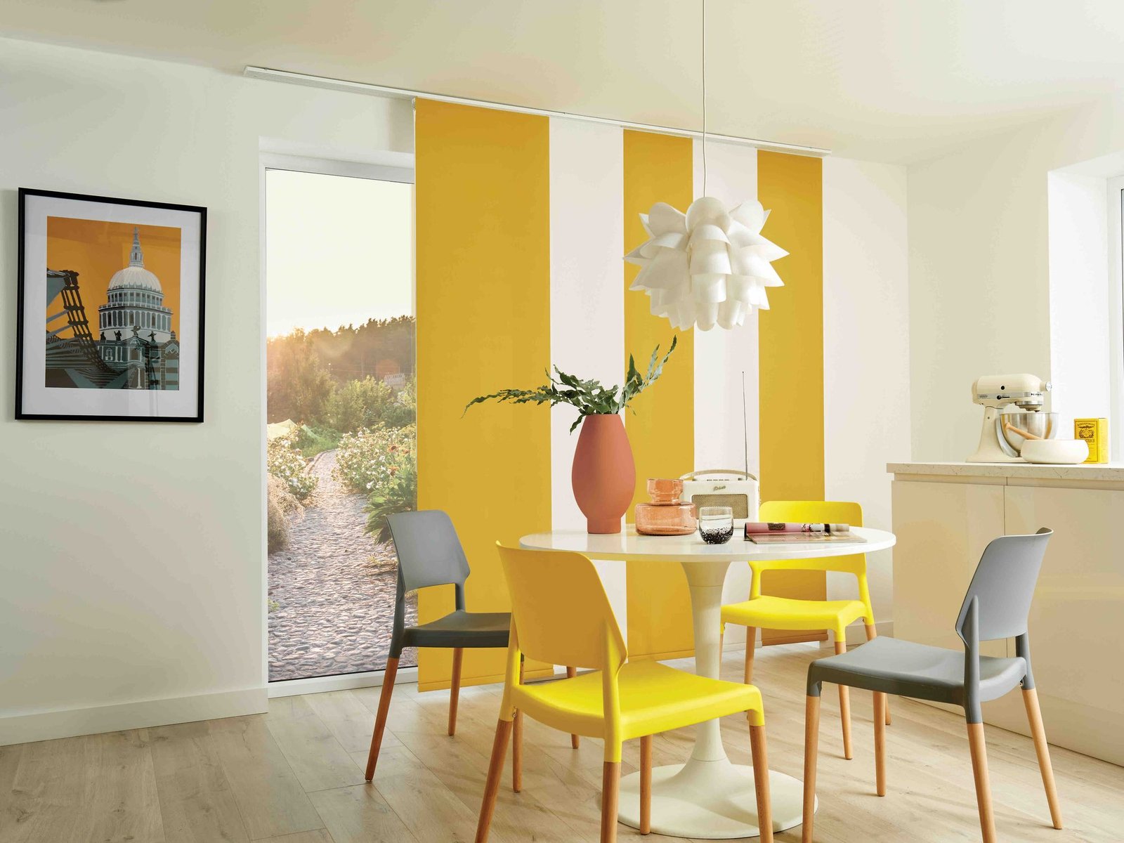 Yellow and white panel blinds partly drawn across a garden door beside a dining table