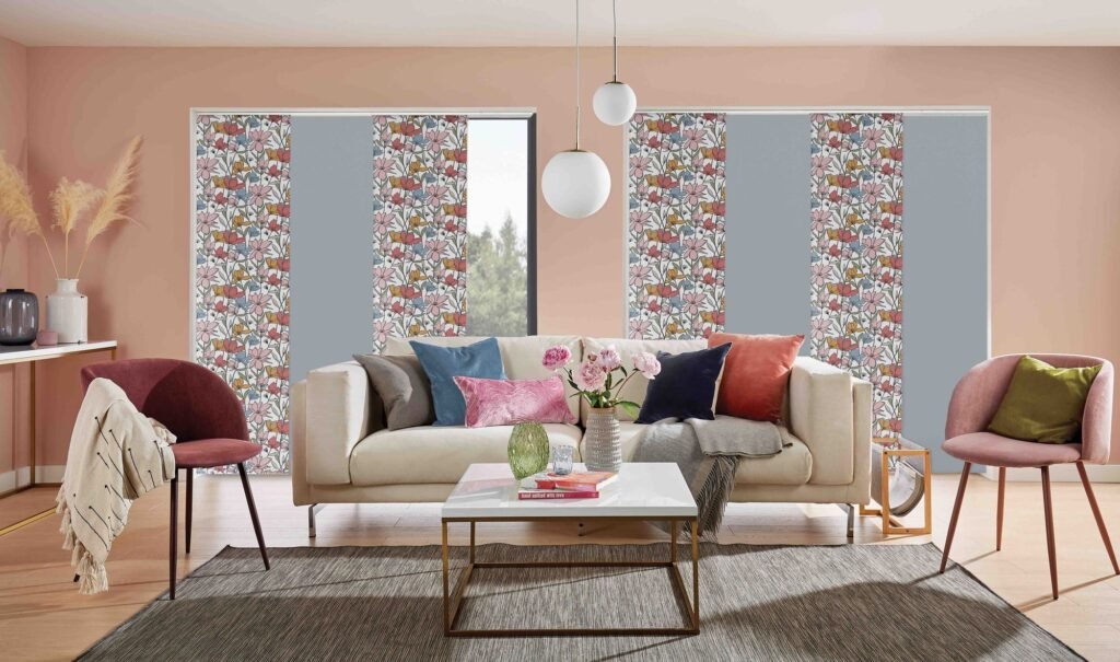 Patterned and plain panel blinds behind a sofa in a blush-pink room