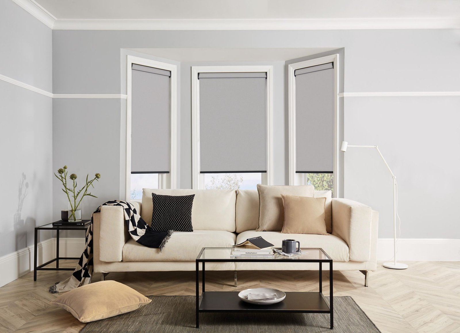 Living room bay window with three grey roller blinds partly raised
