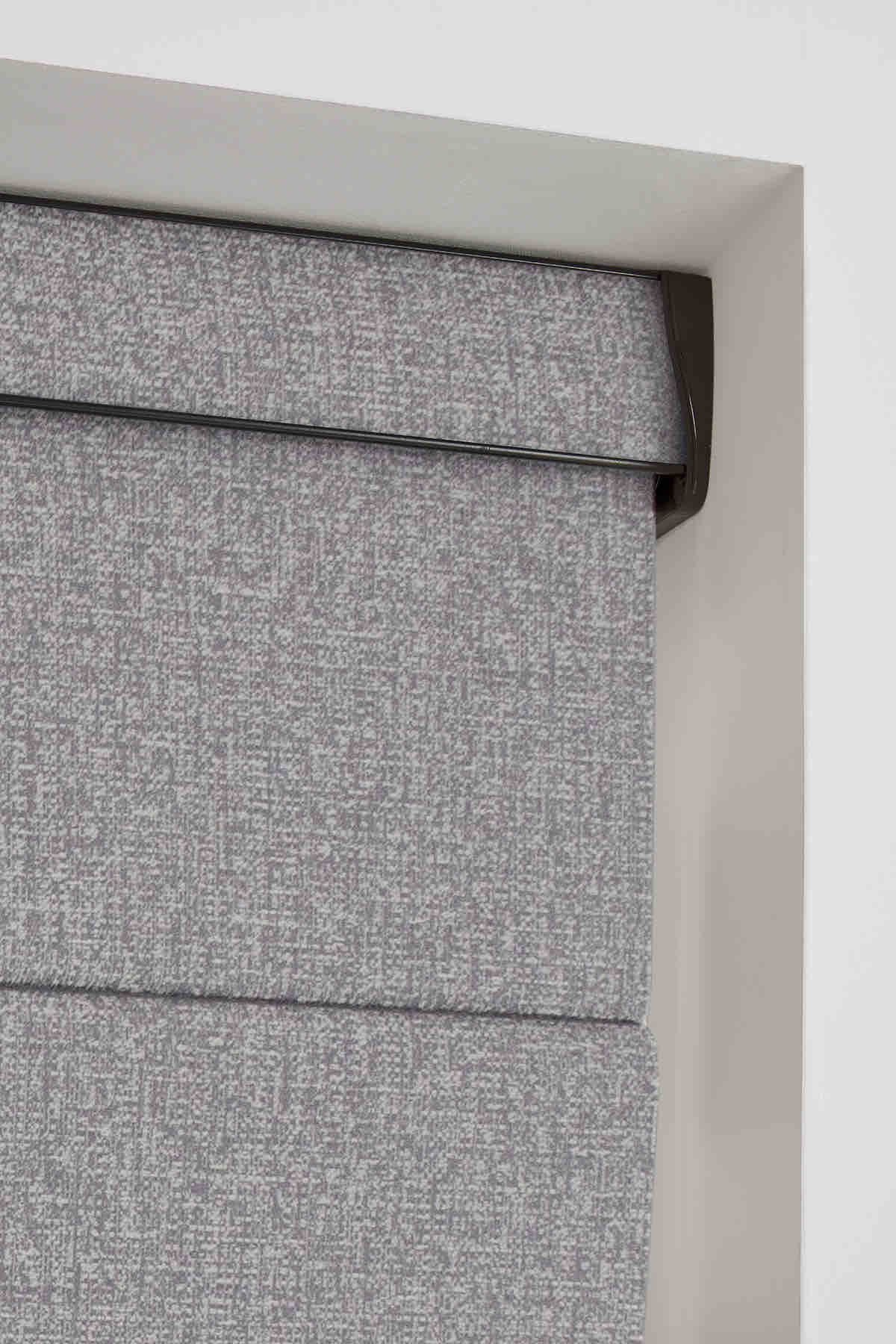 Close view of the stacked fabric folds of a grey Roman blind