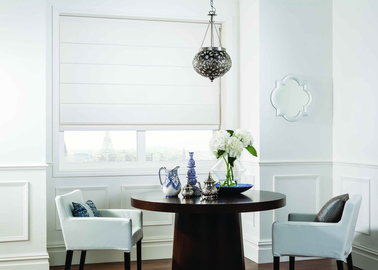 Soft white Roman blind lowered behind a dining table