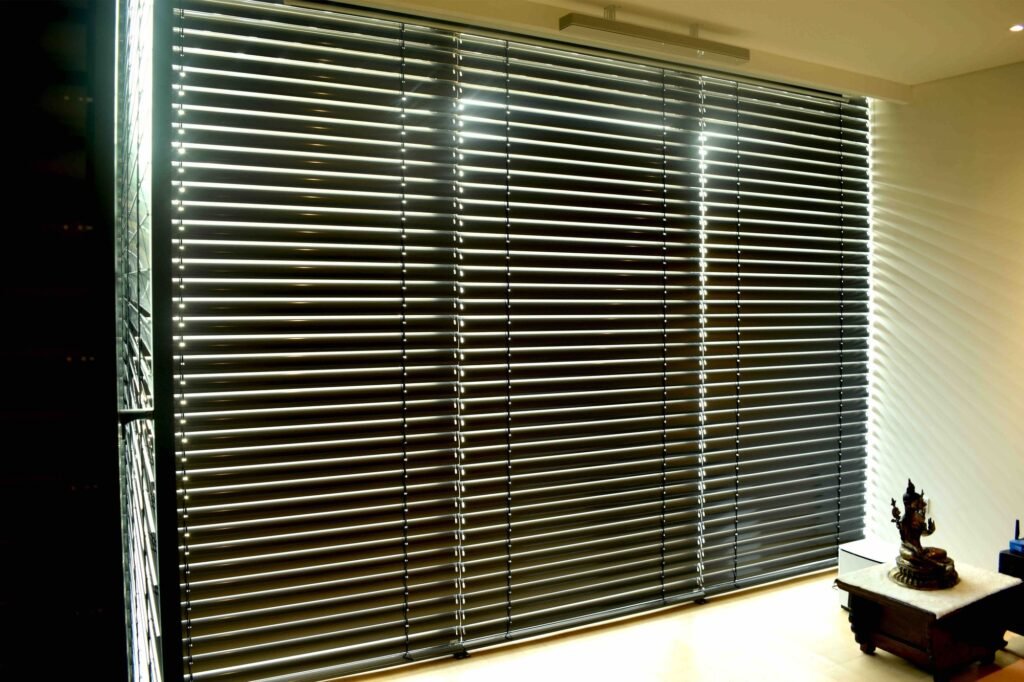 Dark Venetian blinds angled to filter daylight in a corner living room