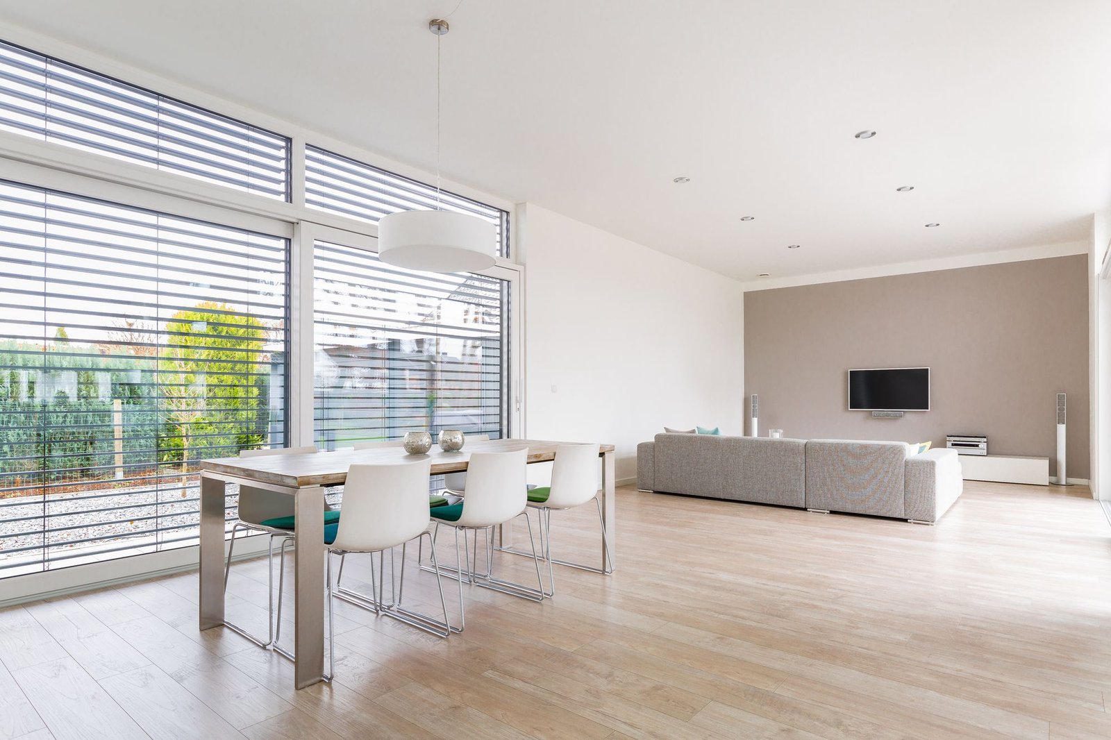 Venetian blinds across a long run of windows in an open-plan dining and living space